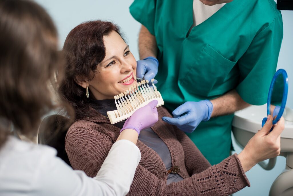A patient smiles as she examines the results of tooth whiteners in Charlotte.