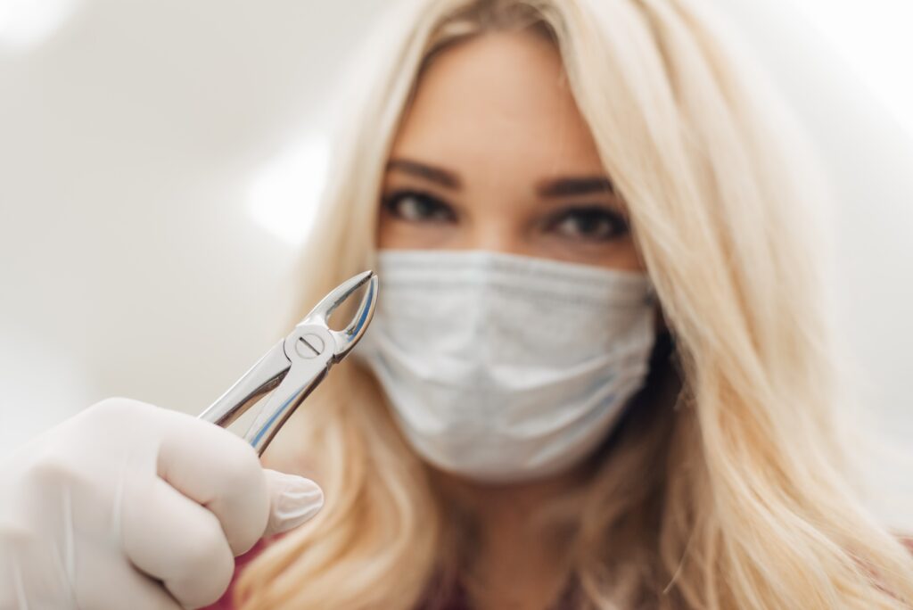 A female dentist holds a dental tool towards the camera, preparing for an appointment for tooth decay removal in Charlotte.