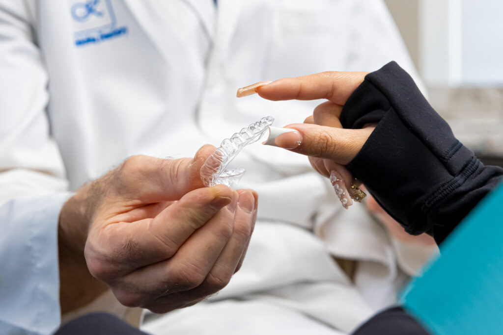 a dentist hands a patient a clear aligner as an overbite treatment in Charlotte